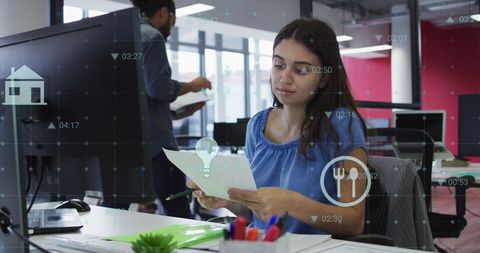Businesswoman Analyzing Documents in Modern Office with Digital Graphics Overlay
