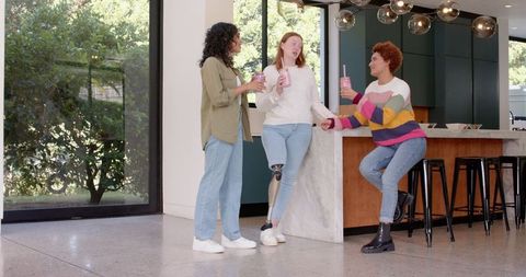 Diverse Female Friends Enjoy Refreshing Smoothies in Modern Kitchen