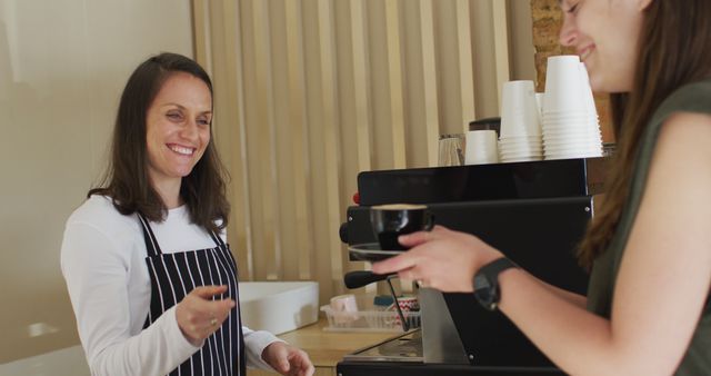 Smiling caucasian waitress wearing apron giving cup of coffee to caucasian female customer. small independent cafe business.