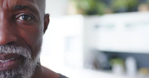 Senior african american man closeup looking at camera in bright kitchen with gray beard