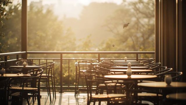 Golden-hour empty cafe terrace basking with round tables, wicker chairs and soft bokeh