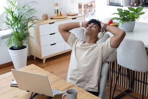 Young african american man relaxing with headphones at home workspace with laptop