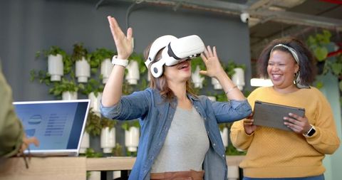 Diverse Team Experiencing Virtual Reality Demo in Modern Coworking Space with Vertical Garden