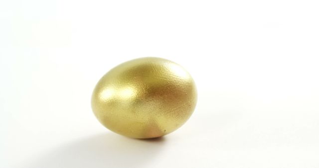 A golden egg is centered on a plain white background, with copy space. Its shiny surface suggests wealth or the concept of a valuable opportunity.