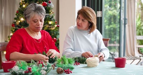Mother and Daughter Crafting Christmas Wreaths at Home