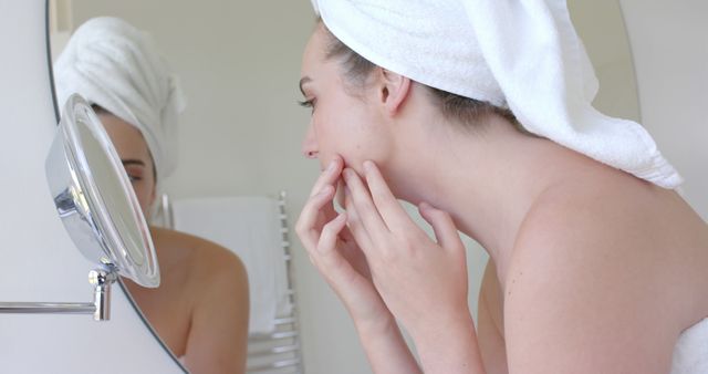 Caucasian woman checking face skin in bathroom at home. Hygiene, health and beauty, and domestic lifestyle concept, unaltered.