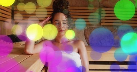 Woman relaxing in sauna with colorful bokeh lights, spa wellness serenity