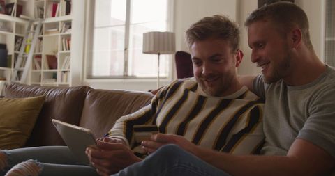 Happy Gay Couple Using Tablet and Credit Card in Cozy Living Room - Download Free Stock Images Pikwizard.com