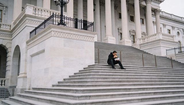 Solitary man eating takeout on marble steps of neoclassical government building