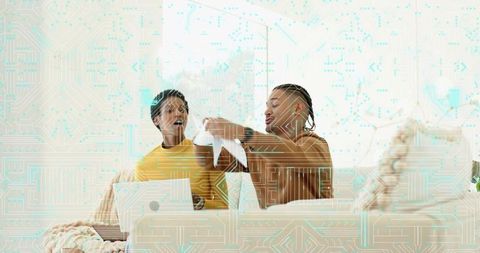 Friends reviewing torn document on sofa with laptop, cozy home collaboration and tech overlay