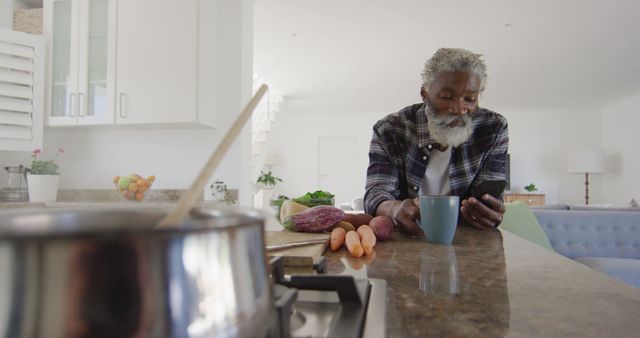 Senior Man Relaxing in Kitchen Checking Smartphone while Cooking - Download Free Stock Images Pikwizard.com