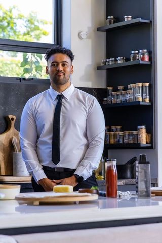 African american man standing in kitchen wearing white shirt black tie with cheese board