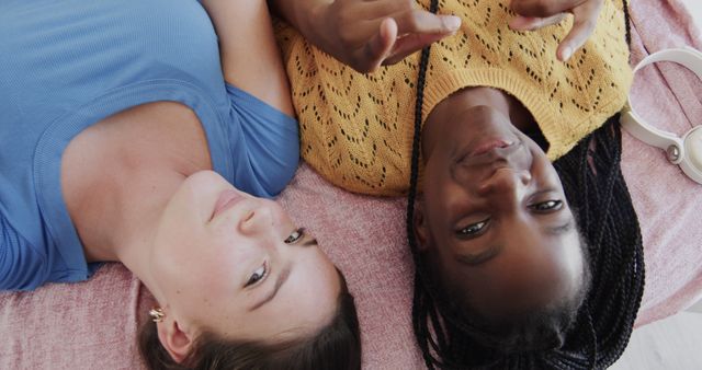 Two friends lying down next to each other, showing their bond and togetherness while relaxing. Use for themes related to friendship, diversity, camaraderie, personal relationships, and stress relief.