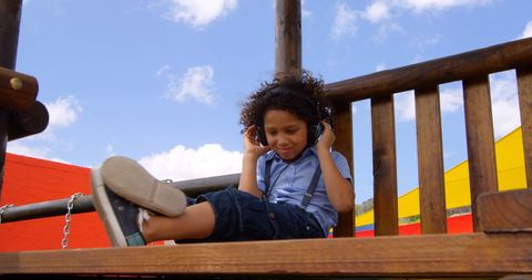 Biracial Boy With Curly Hair Relaxing and Listening to Music Outdoors - Download Free Stock Images Pikwizard.com