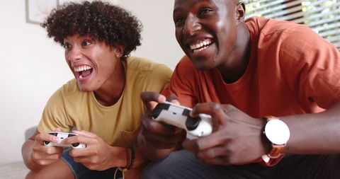 Friends enthusiastically playing video games on couch