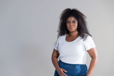 African-american woman standing in white tee and jeans with headband, minimalist portrait