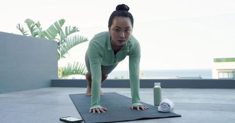 Motivated Asian Woman Holding High Plank on Sunny Terrace