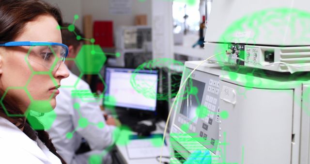 Scientist in white lab coat wearing protective goggles working with advanced technology in a modern laboratory. Another scientist in background working with computer. This image can be used in contexts related to scientific research, technological advancements, lab work, medical research, and professional development in scientific fields.