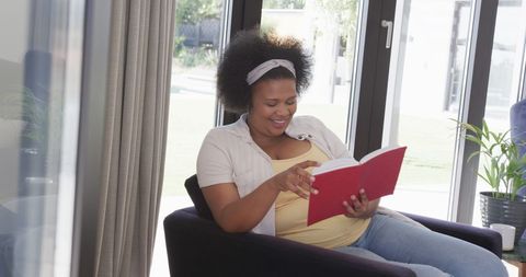 Cheerful Woman Enjoying a Book in Sunlit Living Room