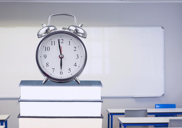 Digital composite image of alarm clock on books in classroom