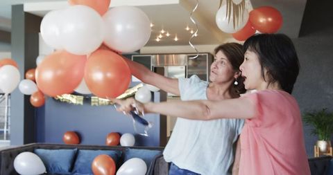 Smiling women arranging balloons for birthday party celebration