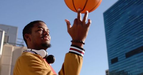Young African American Man Spinning Basketball on Rooftop Wearing Headphones