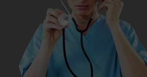 Healthcare professional holding stethoscope against grey backdrop