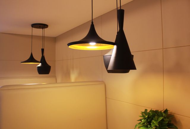 Modern pendant lights illuminate a cozy interior space with a warm and elegant ambiance. The design features sleek, matte black fixtures and a minimalistic aesthetic, ideal for contemporary home decor, stylish cafes, or intimate restaurant settings. Perfect for articles on interior design trends, home renovations, and hospitality decor inspiration.