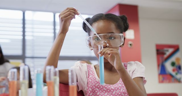 Young girl engaged in science experiment using test tubes in a laboratory setting, wearing safety goggles. Ideal for educational content, STEM learning promotions, children's science programs, or school-related marketing materials.