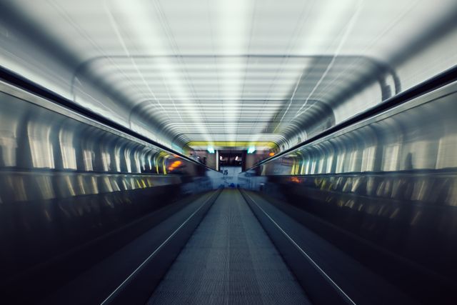 Dynamic depiction of high-speed escalator in a modern underground subway station with motion blur effect. Ideal for illustrating themes of urban movement, transportation efficiency, and fast-paced city life. Can be used in transport-related articles, travel blogs, or marketing urban infrastructure projects.