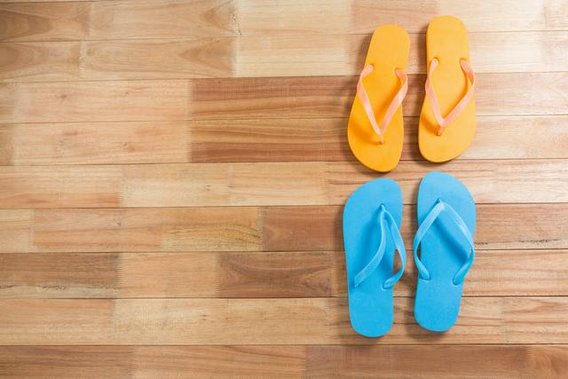 Pair of yellow and blue beach flip flop slipper on wooden board