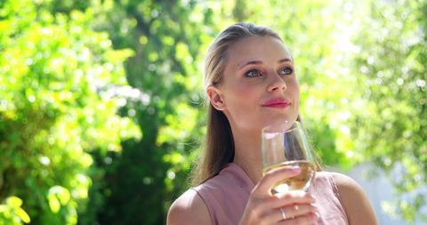 Elegant Woman Enjoying Wine Outdoors in Sunny Garden