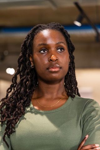 Confident african american woman standing arms crossed in gallery wearing olive top