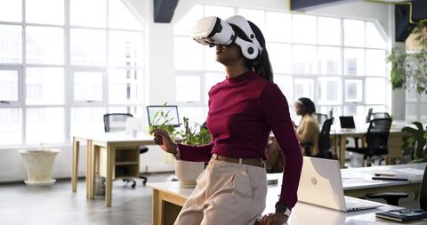 Diverse professional using white virtual reality headset in bright modern coworking office