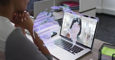 Woman watching laptop during virtual meeting with augmented reality globe overlay