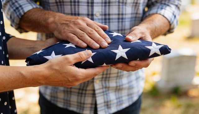Family holding folded american flag at graveside, military funeral, patriotic tribute and honor