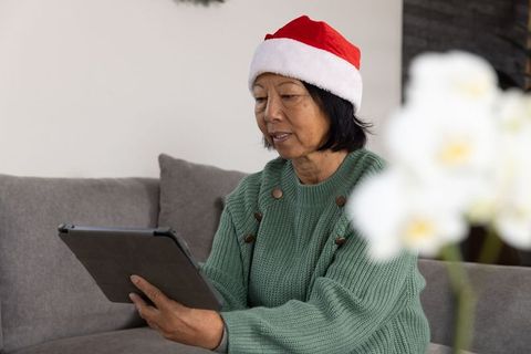 Senior Woman Embracing Holiday Spirit While Using Tablet