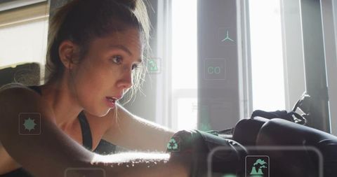 Female boxer catching breath after heavy bag session with hud fitness overlays, backlit gym