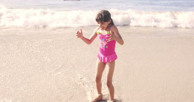 Excited Girl Playing on Sandy Beach Wearing Colorful Swimsuit - Download Free Stock Images Pikwizard.com
