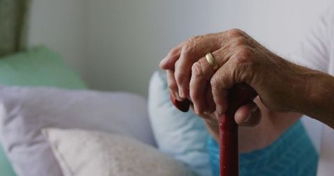 Elderly hands holding walking stick signifying loneliness and hope