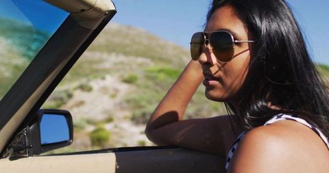 Woman enjoying relaxed drive in convertible on sunny day