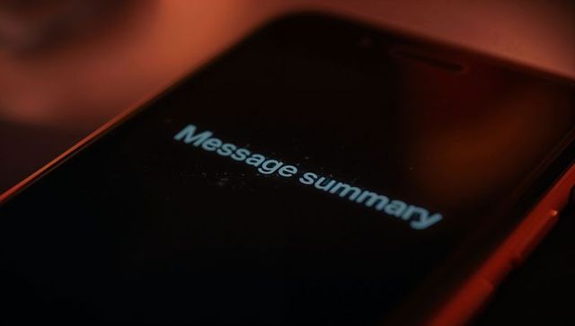 Smartphone displaying message summary with warm rim light and dusty screen