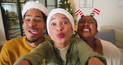 Joyful friends wearing santa hats celebrating christmas indoors