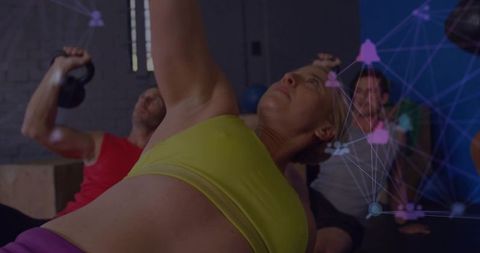 Woman performing side plank with kettlebell in group class with digital fitness overlay