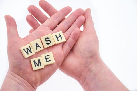 Hands Holding Letter Tiles Spelling 'Wash Me'