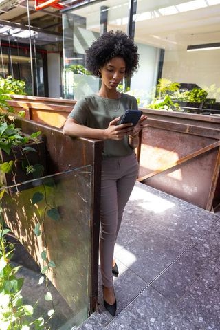 Professional woman checking smartphone in modern green office