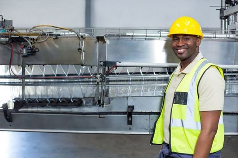 African american industrial worker in bottling plant wearing hard hat