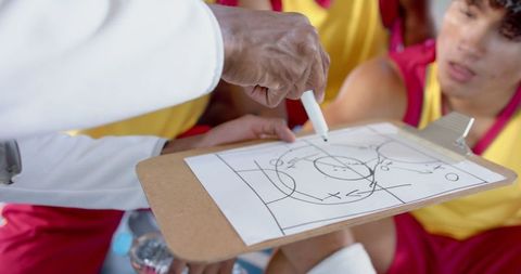 Basketball Coach Drawing Strategic Play for Team During Passionate Huddle
