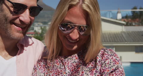 Joyful Couple Relaxing by Poolside with Smartphone in Sunny Summer
