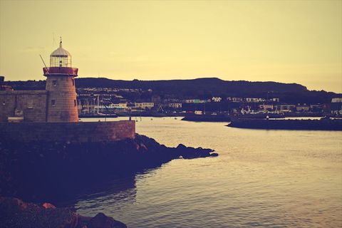 Lighthouse Silhouette at Sunset Over Calm Waters